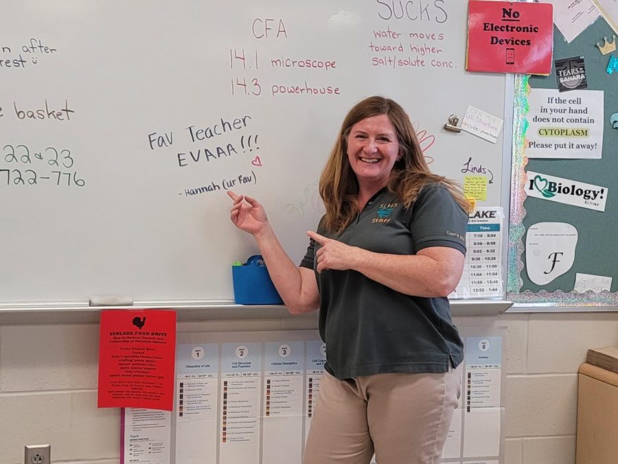 Ms. Pugh, enthusiastically pointing at her whiteboard, where written is a lovely message!