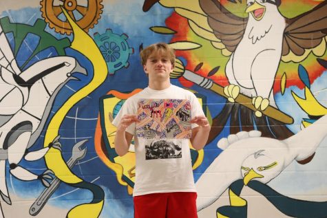 Sophomore, Brayden Jawan, holding a work of his choosing Infront of the school mural.