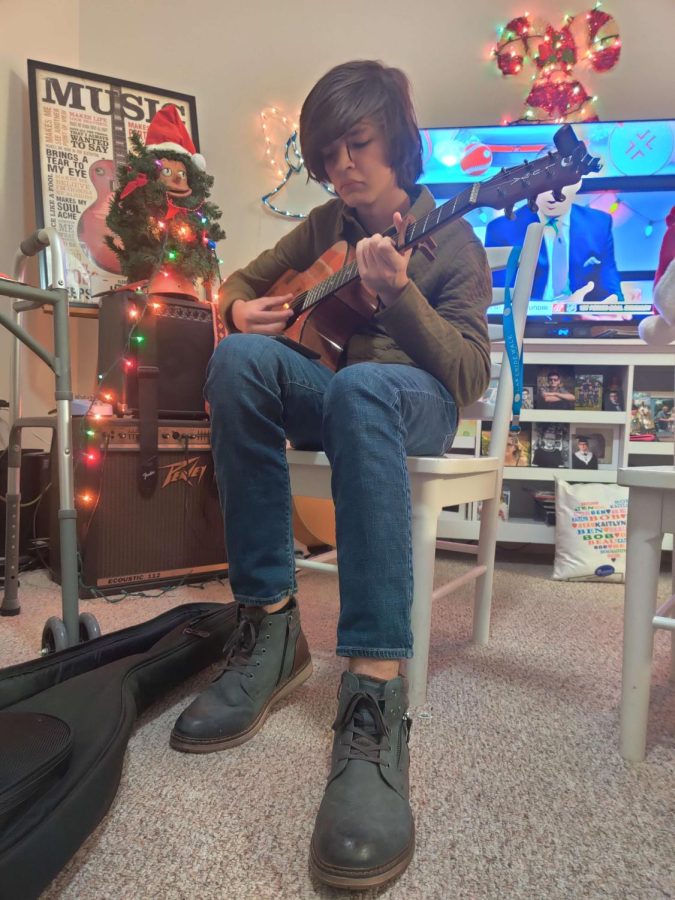 Sophomore Beau Hock practicing guitar and playing silent night.