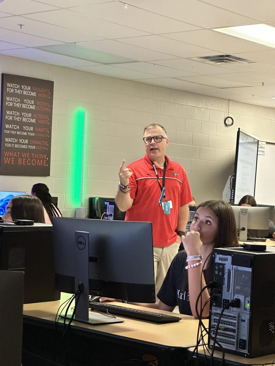 Mr. Webster, in action, teaching students how to use different programs during the Yearbook class.