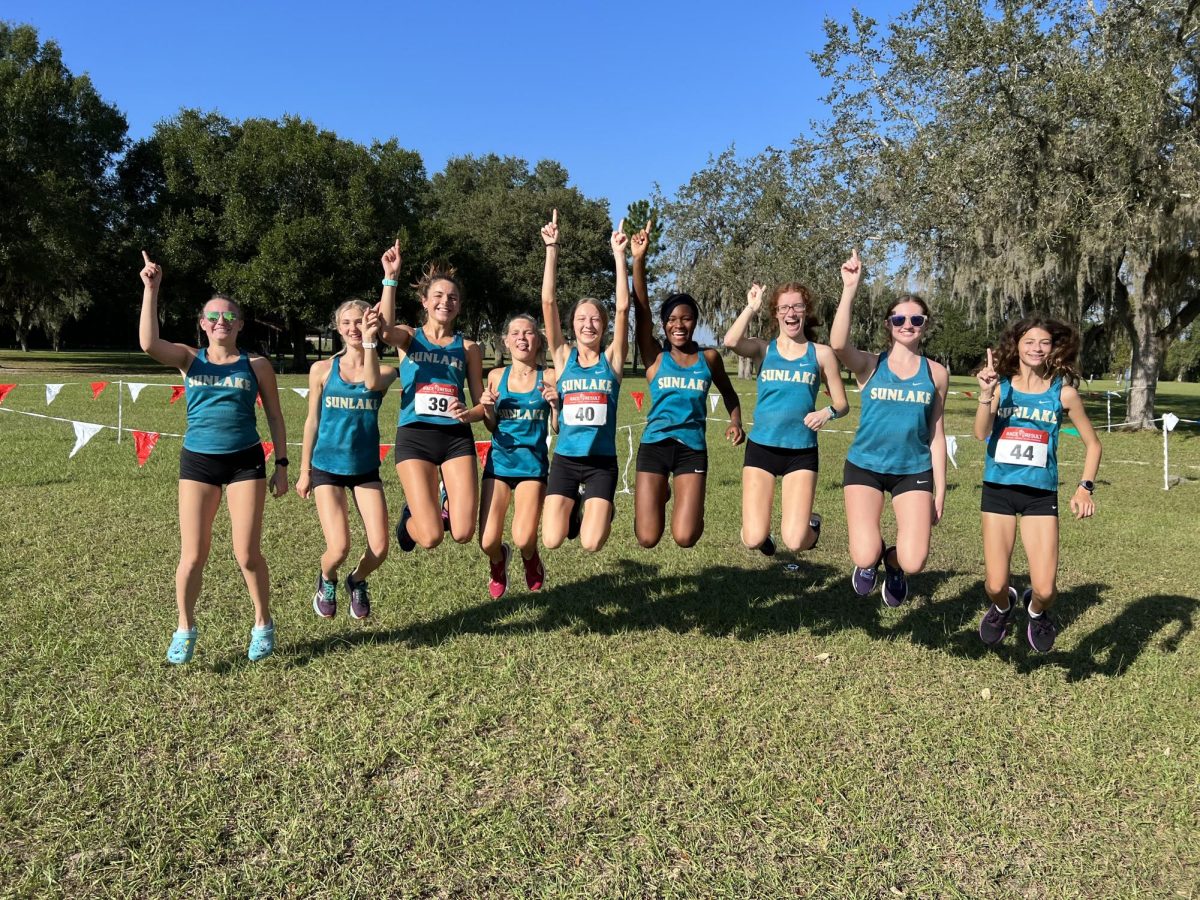 The Sunlake cross country girls jump for joy after their Conference win. Freshman Katelin Wilcox, one of the fastest runners in the state, is in the middle of the photo. She has both of her arms raised in the air, holding up the number one. Katelin expresses, I was proud of myself and my team because we did amazing and we won! Im excited to see what we can do next.