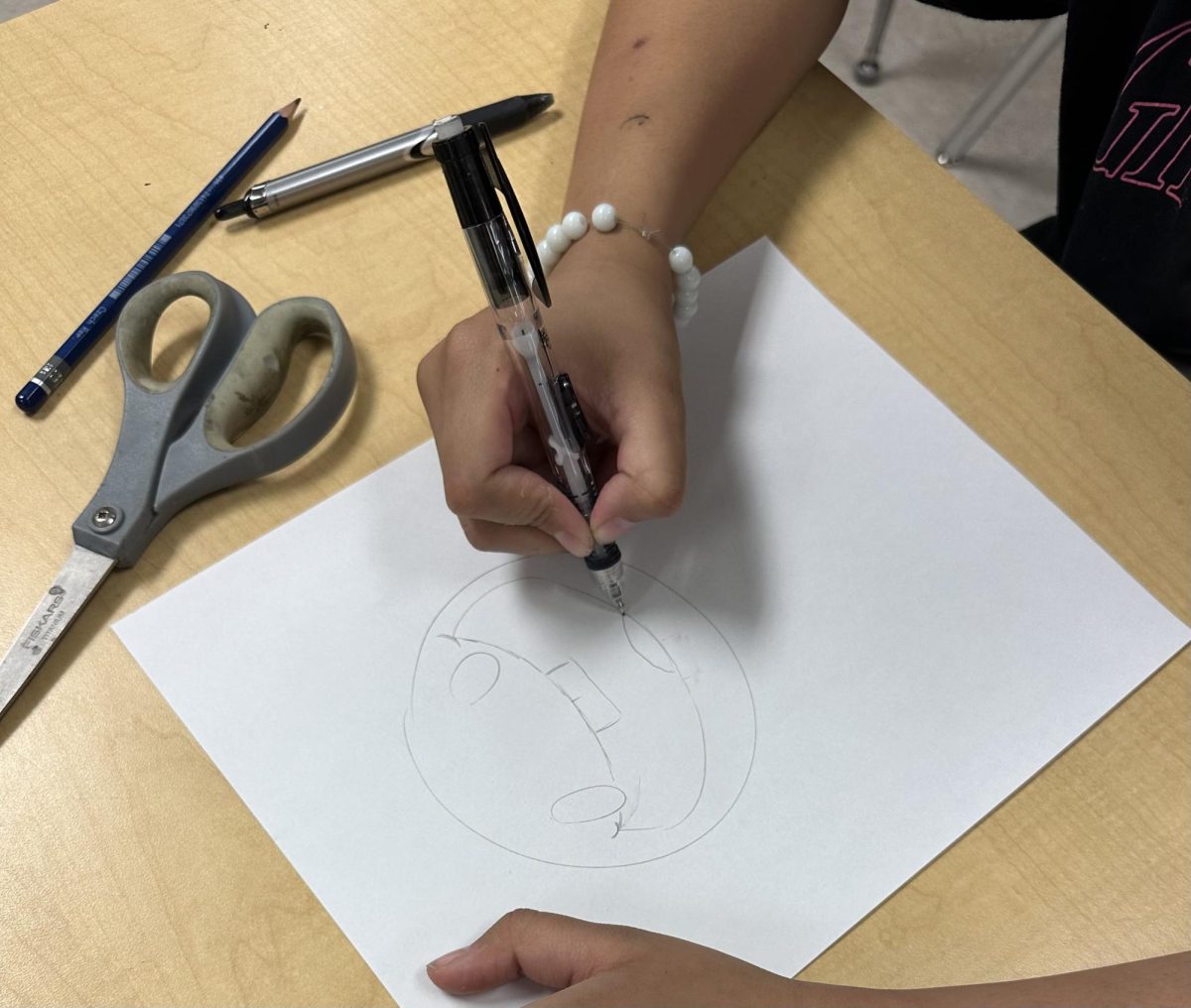 Junior Cameron Witkowski doodling on a piece of paper. Cameron enjoys working on a variety of projects in his art class. He recently completed a still life art project.