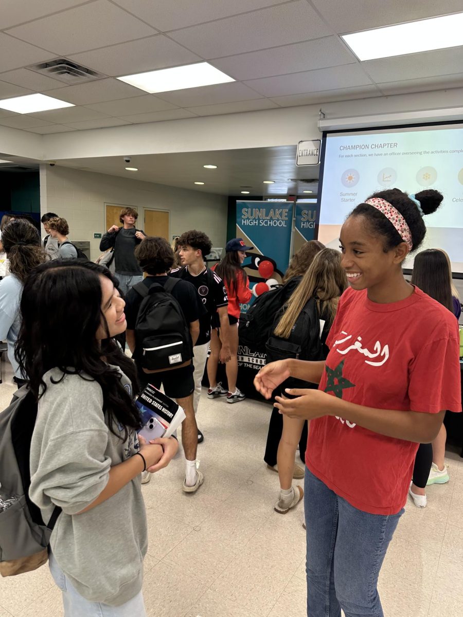 FBLA club officer, Nora Ware, discussing FBLA committees with Amelia Sitoy at a club meeting held in the cafeteria. Amelia is a new member of FBLA.
