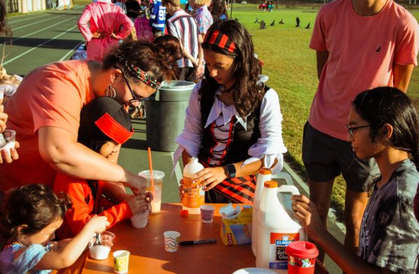 Senior Stefany Miranda, president of the National Science Honors Society, is showing kids attending her station how fun science can be. To show the children, she is guiding them on how to make slime. She is also showing her Halloween spirit by being dressed up as a pirate. 