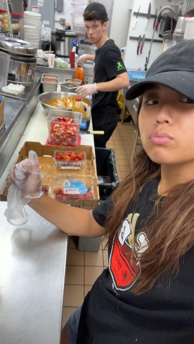 Senior+Melina+Nguyen+%28right%29+working+one+of+her+shifts+at+Fish+Bowl.+She+is+cutting+up+strawberries+for+Fish+Bowls+infamous+acai+bowls+with+her+coworker+Nick+%28left%29.