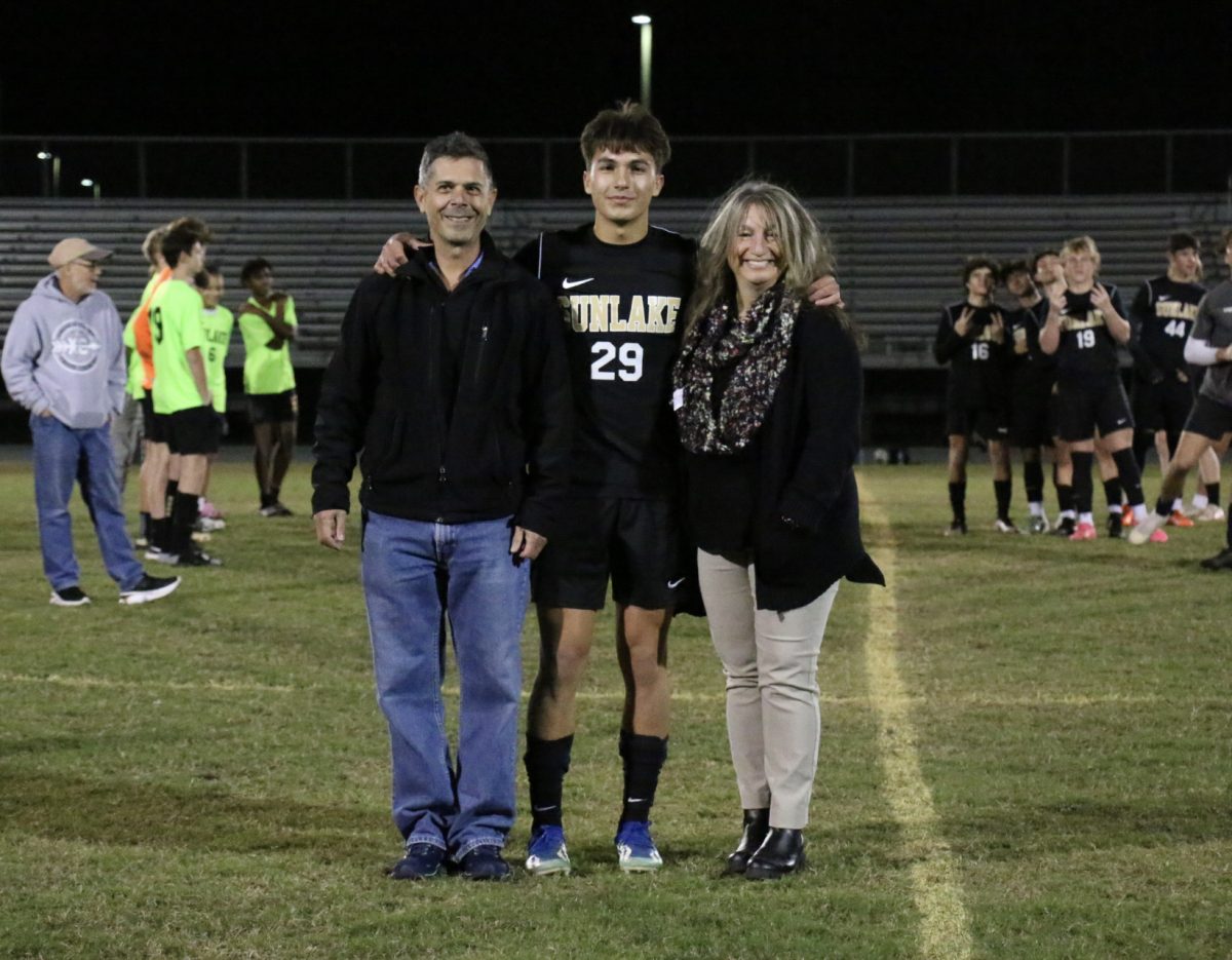 Senior Nicholas Elgin, on the field with his mom and dad. He had just walked between all his Sunlake teammates as they cheered him on. He said, Knowing its my last semester in high school is exciting since Im ready for college, but I know I will miss it.