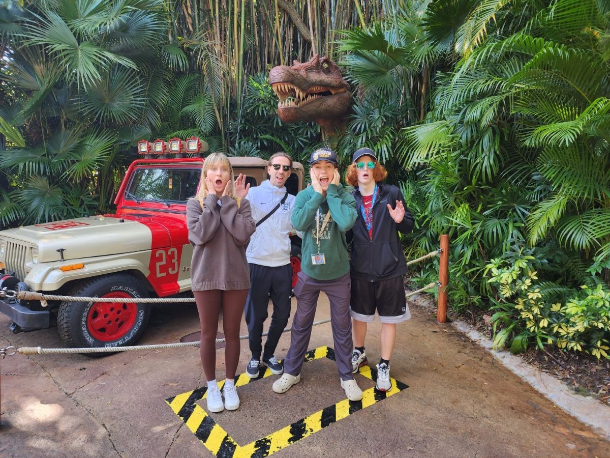 Jack Svendgard with his family at Universal Studios. They are posing and standing near the Jurassic Park area at the park. 