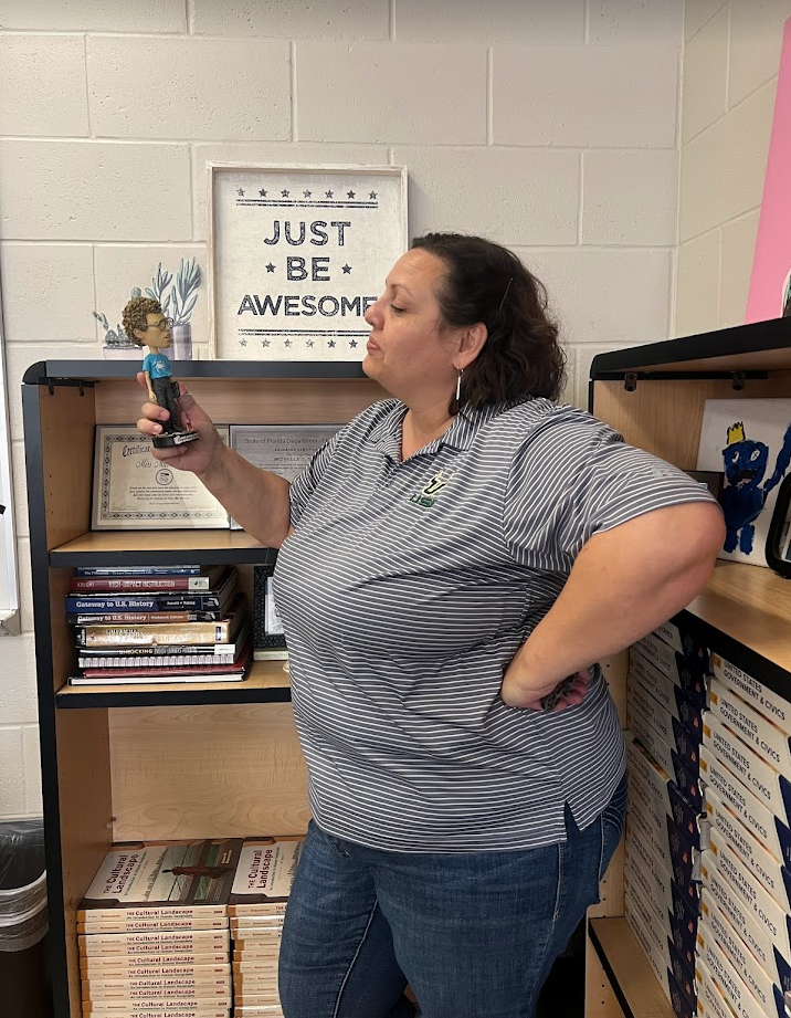 Ms. Stover teaches students as young as freshmen and as old as seniors. Ms. Stover stands admirers her Napoleon Dynamite figurine along with other fun items on her shelves. She is a great teacher and even says I dont see value in giving homework.