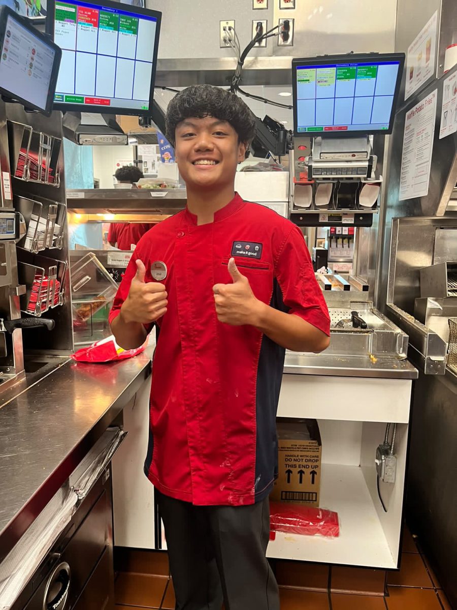 Senior, Jonah Romero, posing for a picture at Chick-Fil-A in his work uniform.