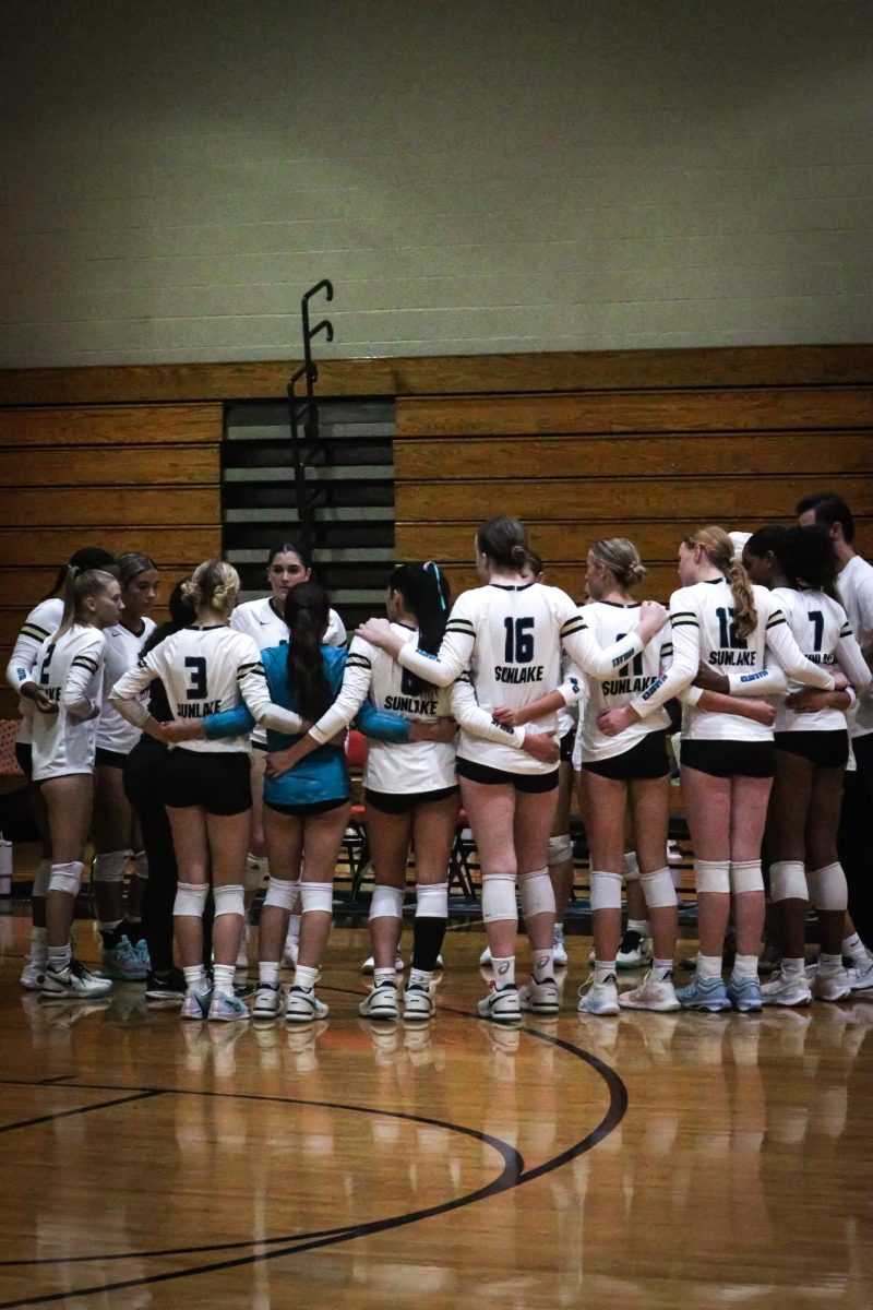 The Sunlake varsity volleyball team in a huddle during a time-out