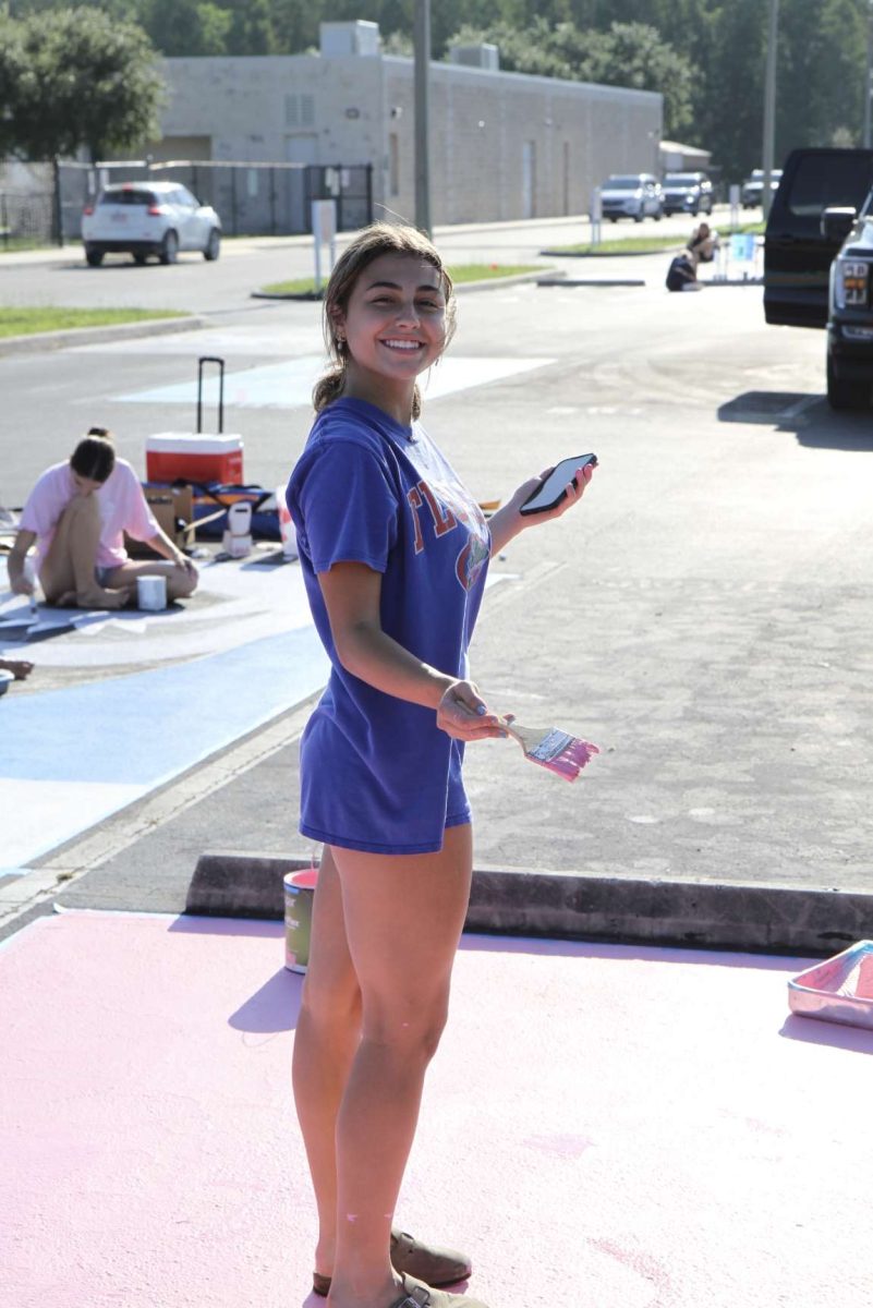 Claudia can be seen at her parking spot. Claudia is painting her spot smiling.