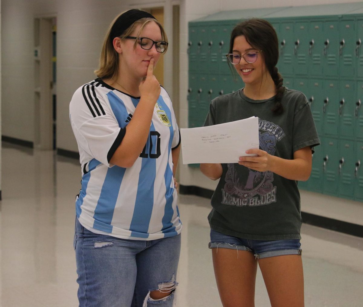 On the right is Mia Lanier and on the left is Sadey Mathis Mia is showing Sadey the blueprints for the scenes they have to paint. She is very excited for this years skit end results.