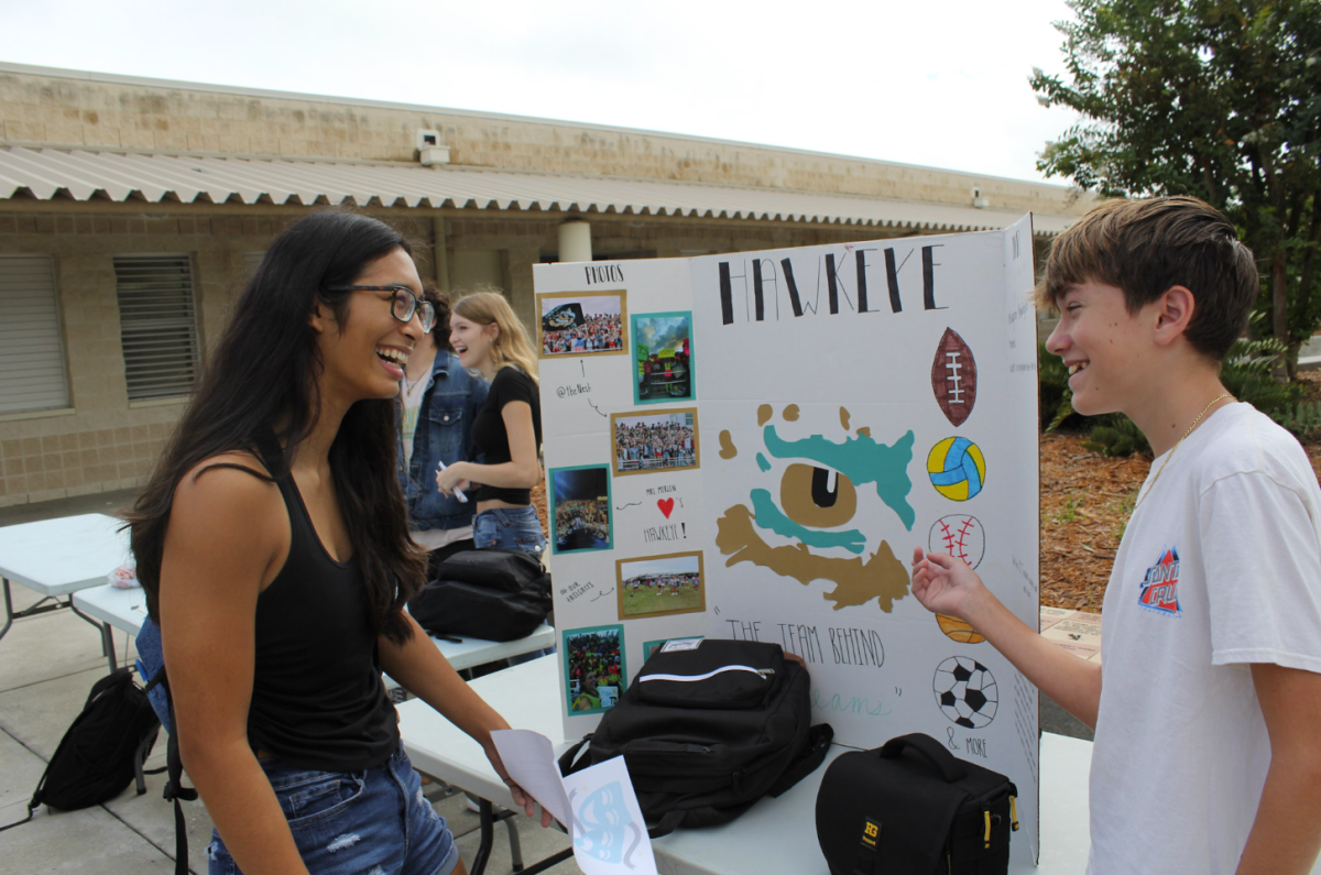 Freshman Luke Downey speaking about the Hawkeye Spirit Club to other students at the club fair. He believes the club is a way to get students move involved in the Seahawk Community. He made sure to thoroughly sell the club to every student who passed by. 