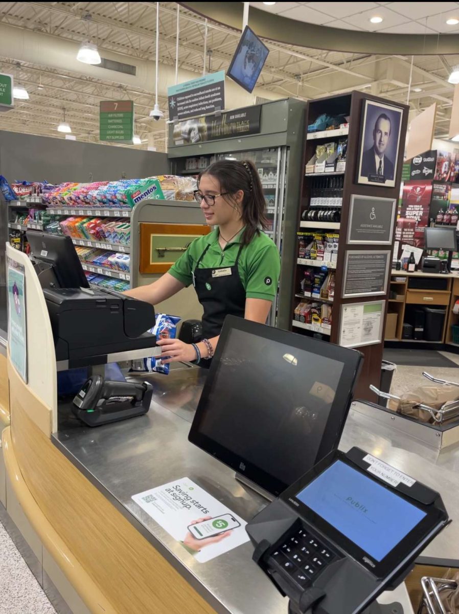 Izabella Kullman, Senior; working hard to contribute to the American way of life. Izabella works as a cashier at Publix. It is her first job and she loves the "good environment" there while she "saves up for a car". (Photo was used with permission) 9/9-13.