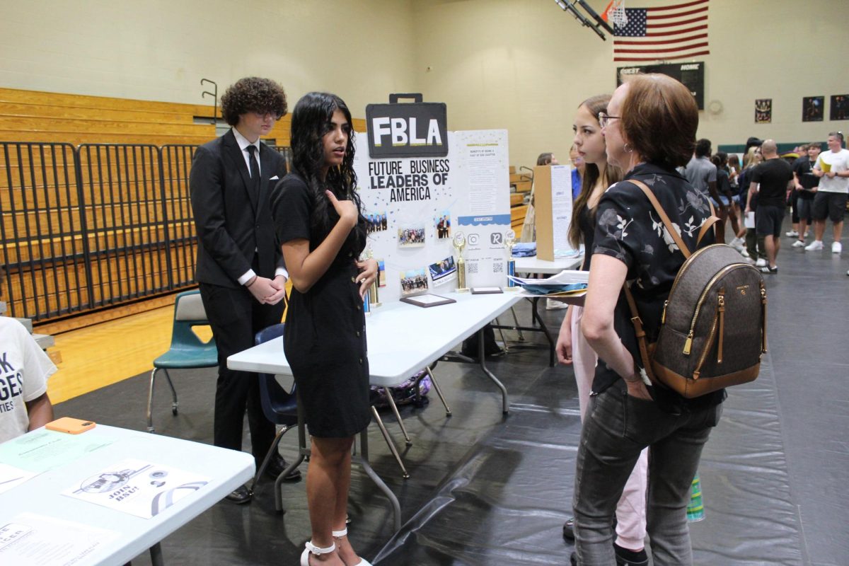 Arbina talking to a new student and their parent, explaining what her club does. Arbina talked about this, saying, "I had some people who were very excited about FBLA... Similarly, I spoke with some families where the student was more shy and interacted with the parent instead. Every interaction was different."