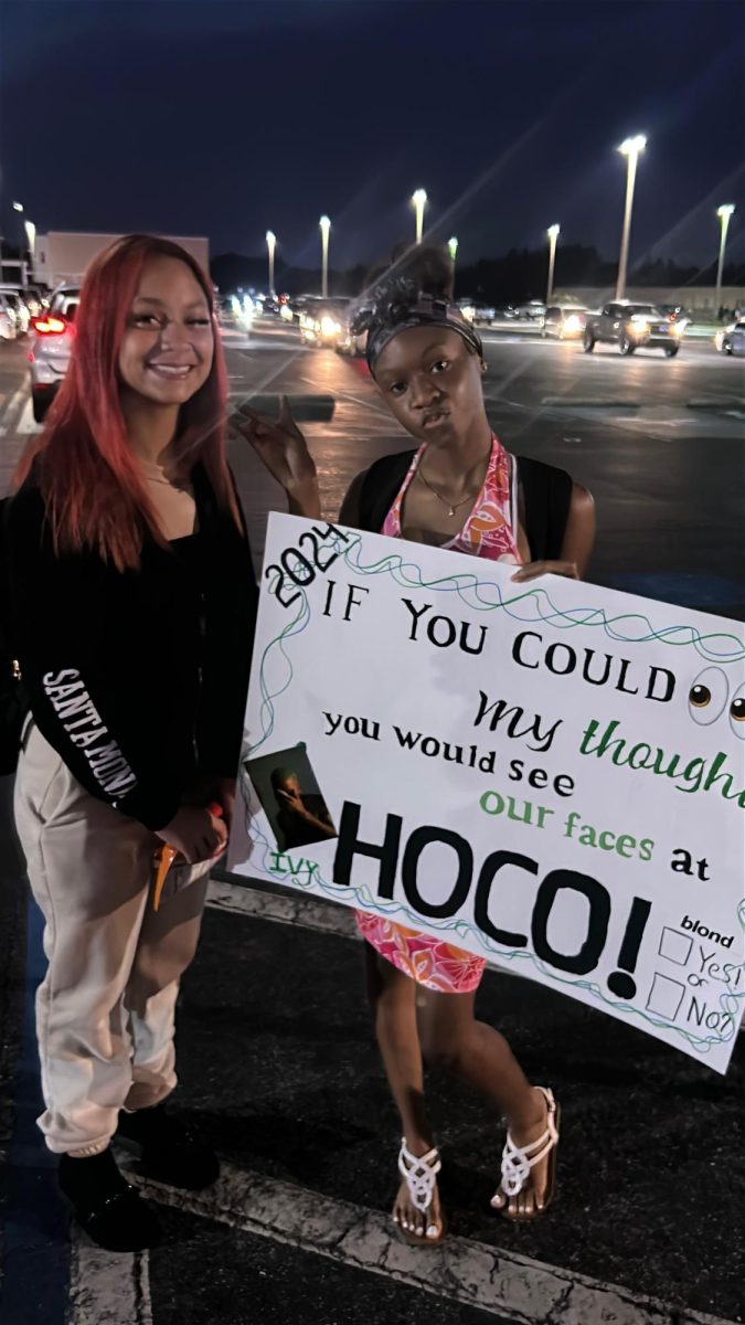 Isis and Alani posing with their hoco poster 