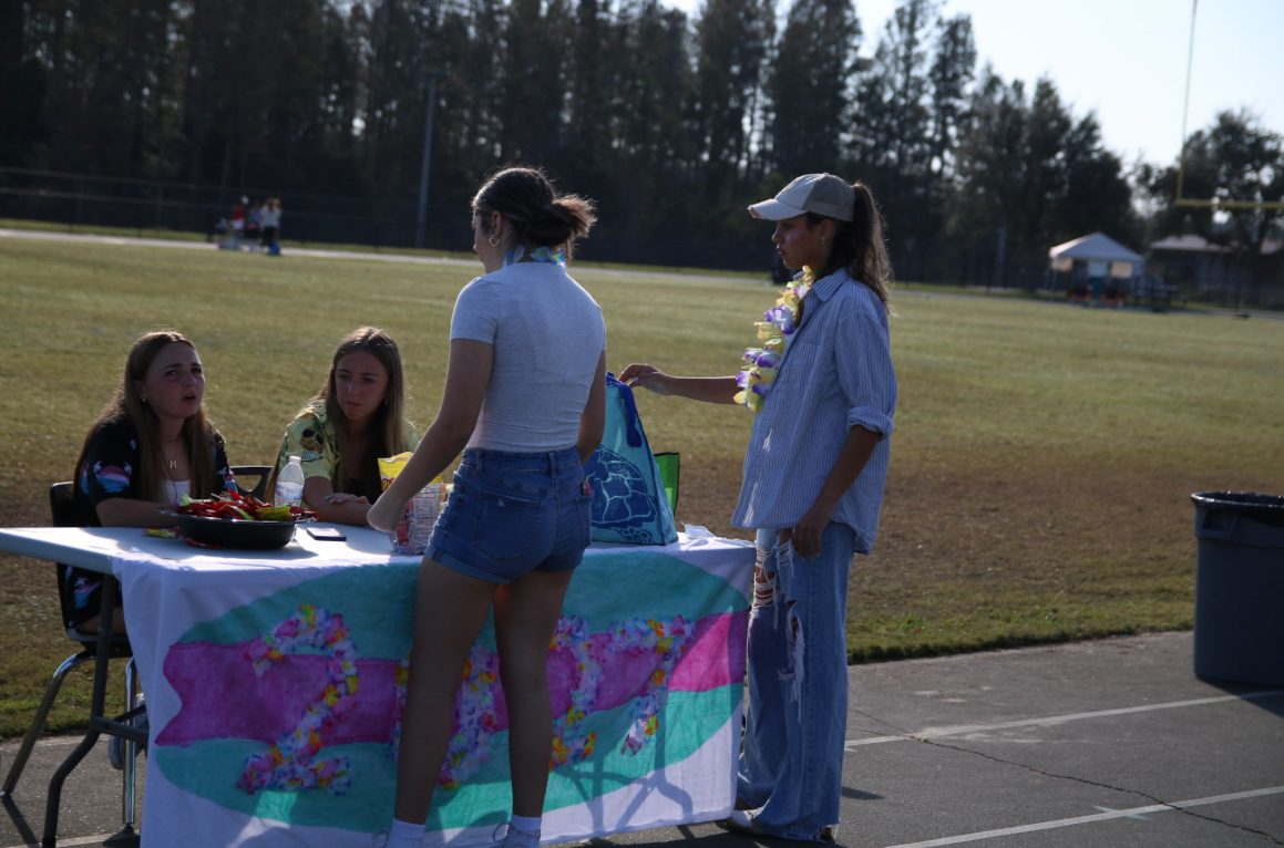 Sophomores, Audrina Amador (Standing, Left), and Annele Castillo (Standing, Right), run the Class of 2027 booth along with other members of the class of 2027 student council at Trick-Or-Treat Around the Track.