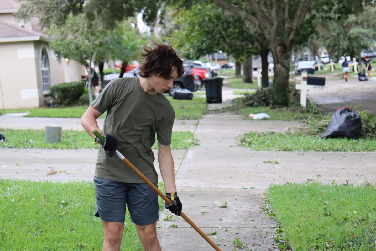 Caleb is seen in this photo. he is picking up leaves with the rake. it took them hours to clean up. 