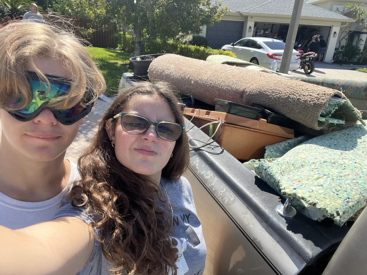 Taylor and a family member standing near a truck of debris from hurricane Milton.