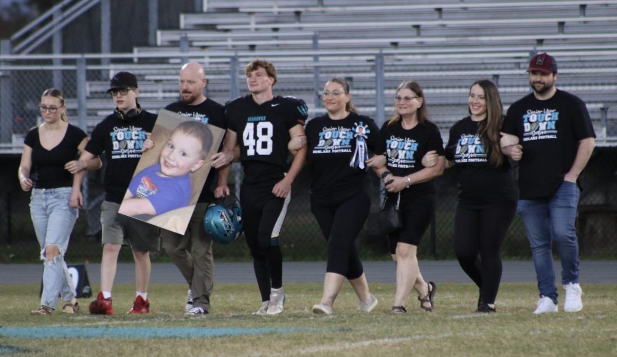 Matthew walks onto the field with his family on Senior Football Night. 