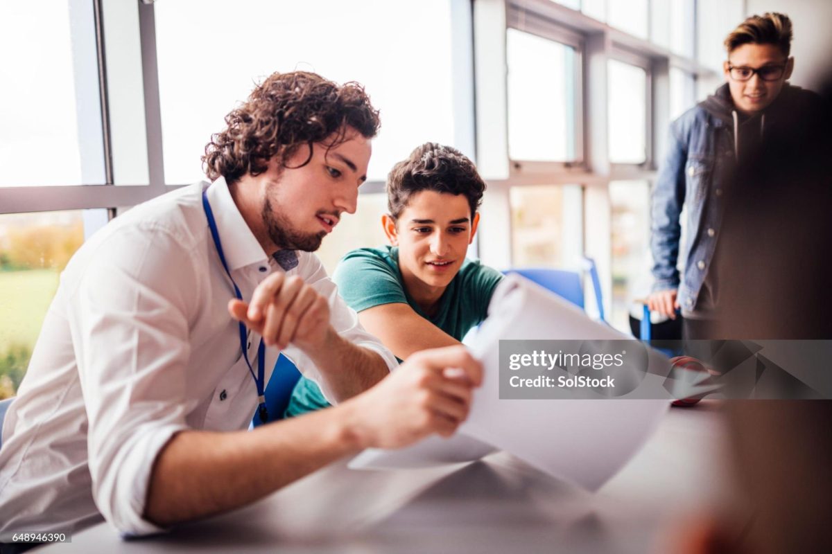 ("Teacher helping student with work", Getty Images)