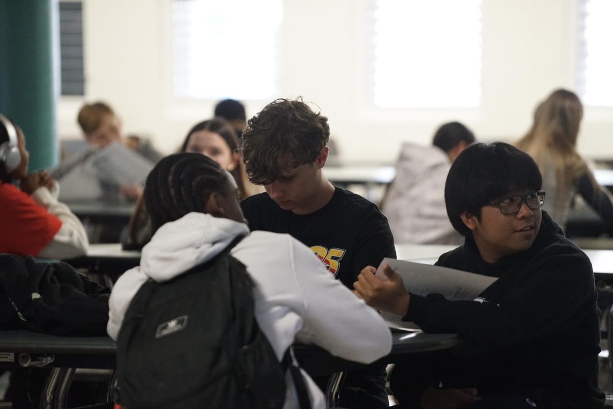 Kodes and students reading their packets and listening to the meeting.