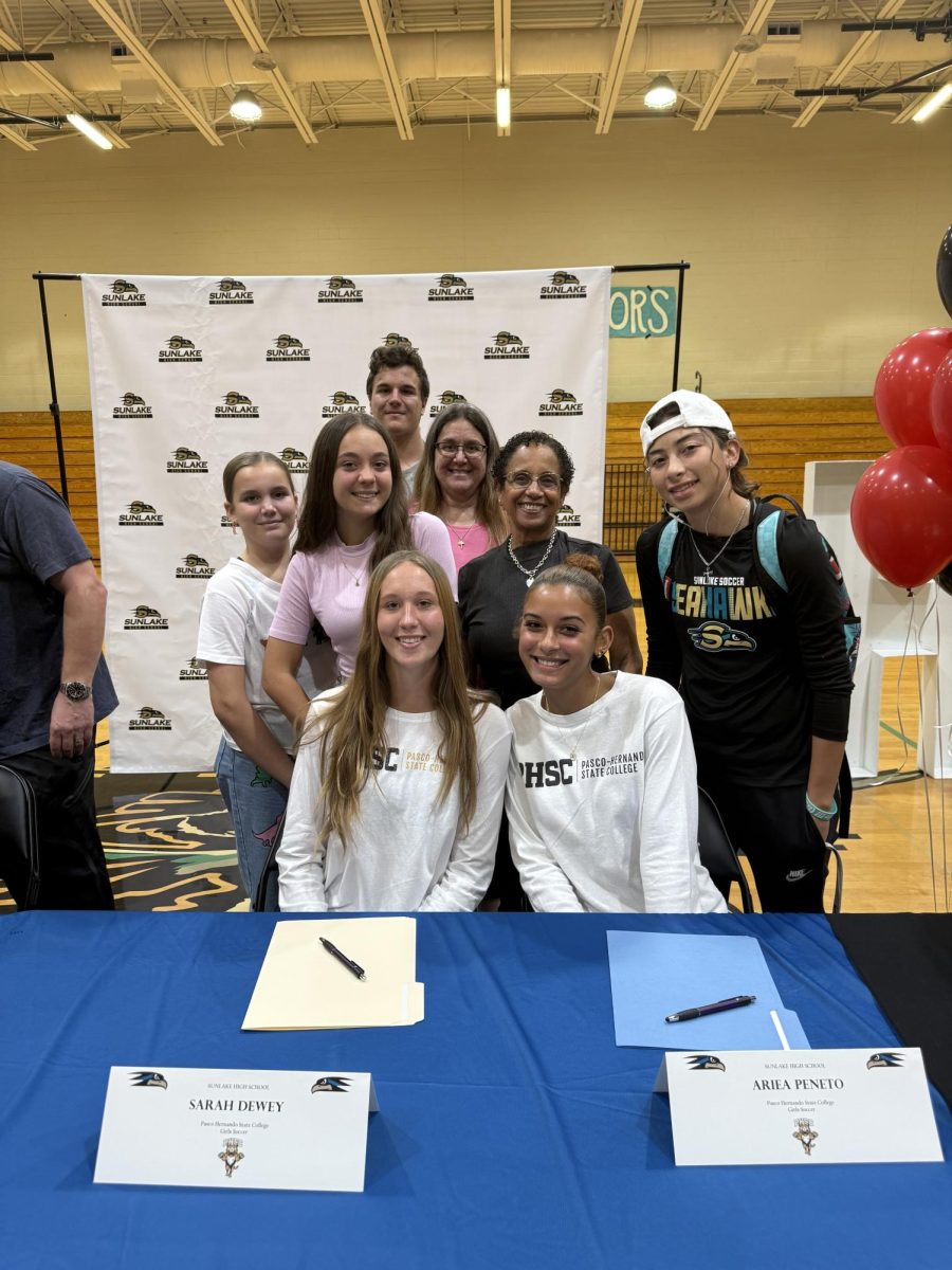 Sarah Dewey (left) and Ariea Paneto (right) smiling with their families right after signing their forms.