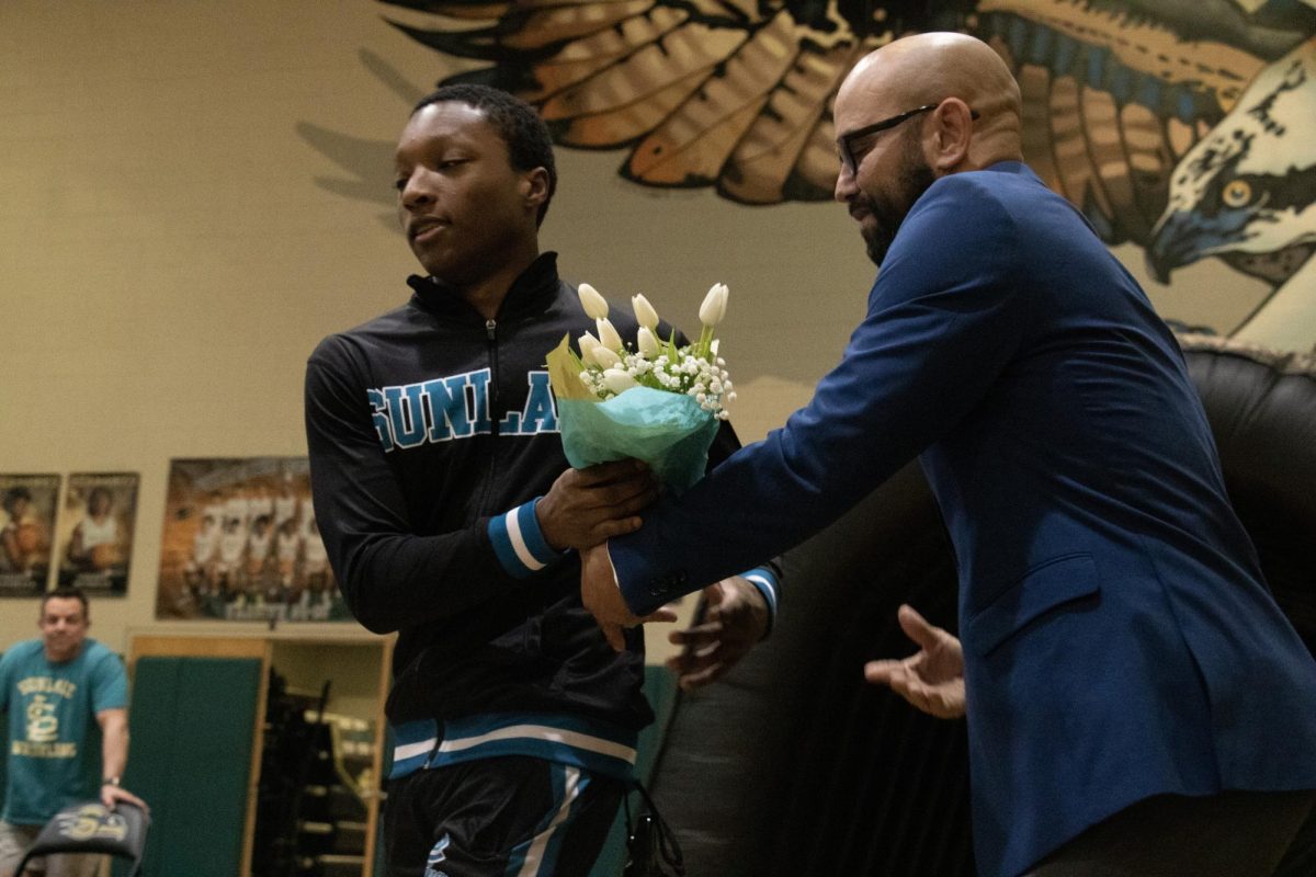 Johnny Fields (12th grade) accepting a bouquet of flowers from his coach during Wrestling Senior Night. 