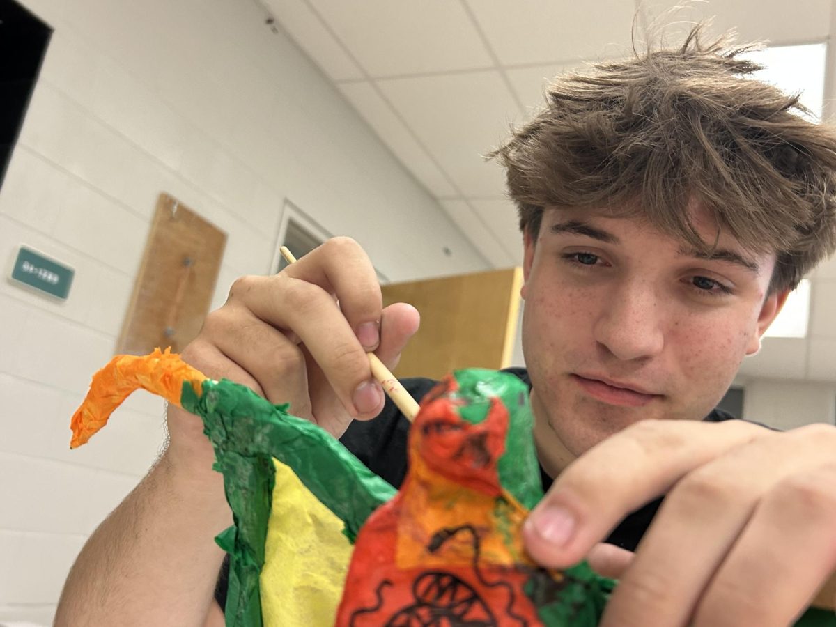 Zachary Fishel (11th Grade) continuing to apply glue to his project.