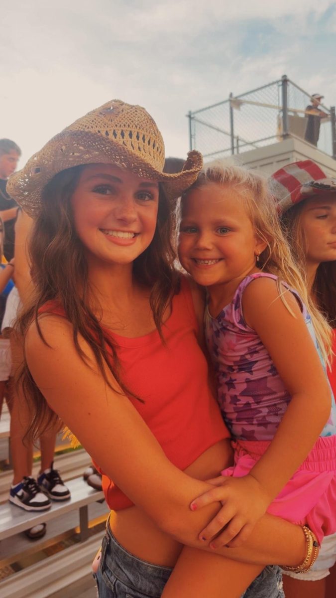 Taylor Van Brocklin having the best time at the very first football game of her freshman year with her friend's little sister in her arms. 