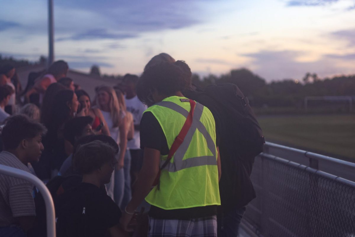Jerome Guirgius, senior, laughing with friends while wearing a Hi-Vis vest during senior sunrise.