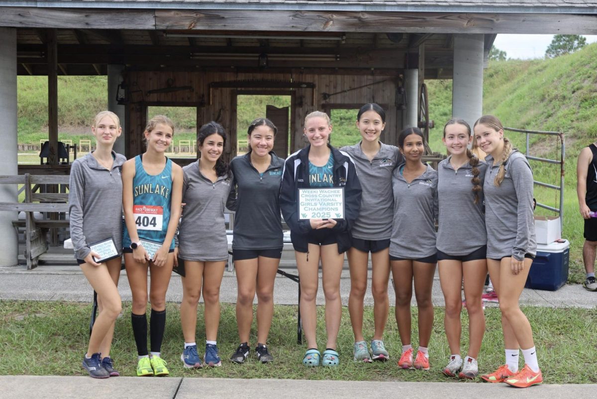 the girls cross country team standing with their champions sign