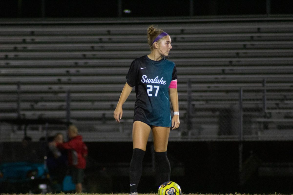 Aubree Brown gets behind the cone, preparing herself for her practice kick before the game. Taking a deep breath, she runs towards the ball, kicking it perfectly into the goal.