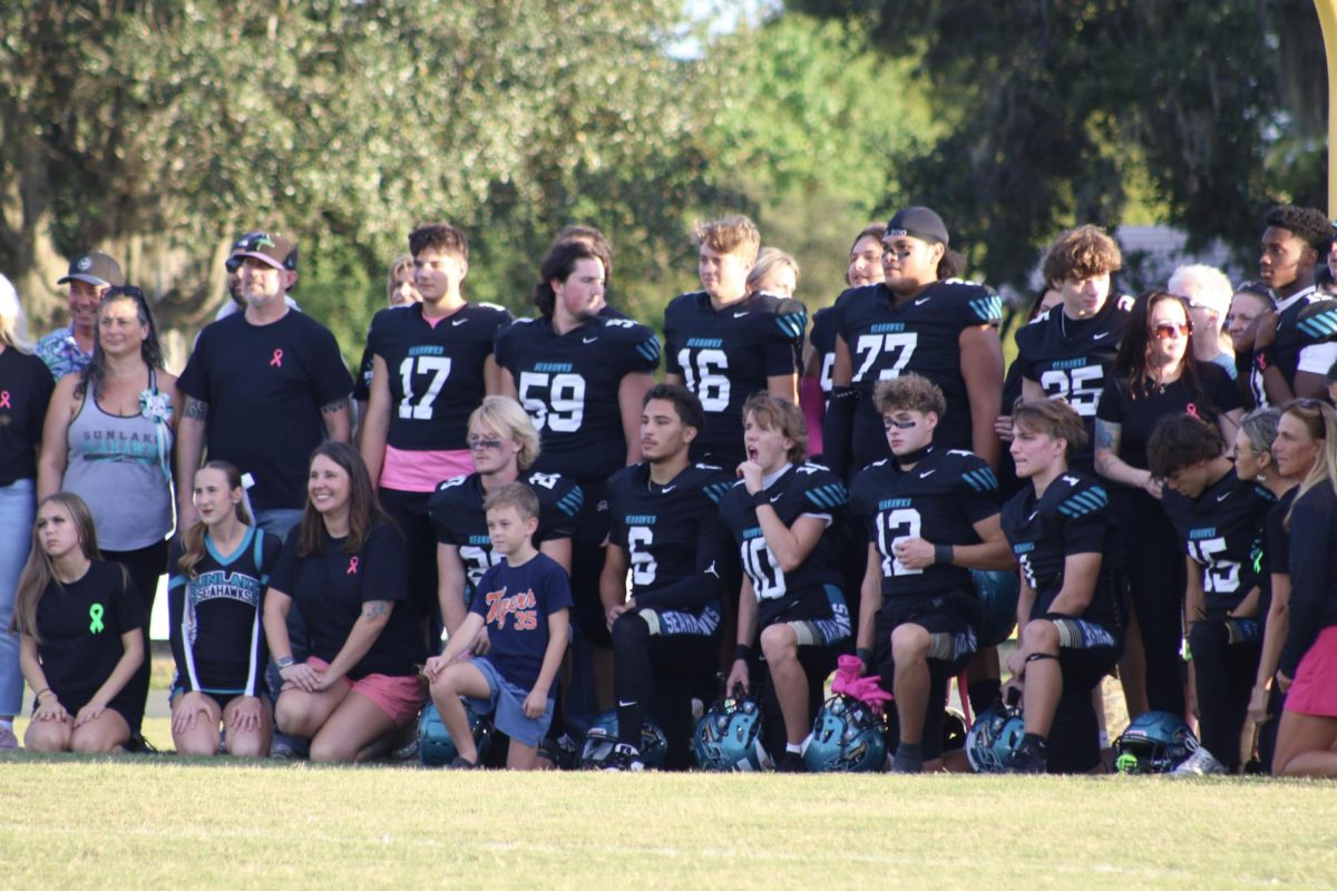 All of the footballers and cheerleaders sitting down waiting for the senior walk to happen.