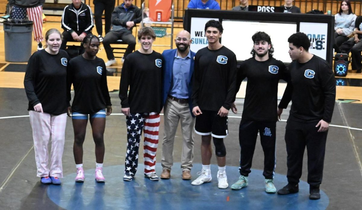 Alfonso Alfaro and the rest of the graduating seniors taking a picture at their wrestling senior night. Alfonso is the third boy from the right.