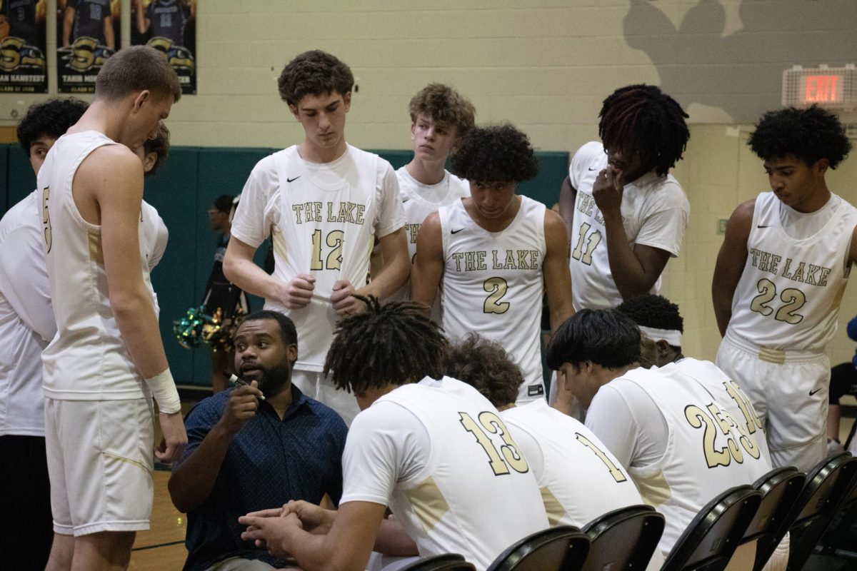 Senior Leon Jones (#2) listens closely during a timeout as the team gathers around their coach. Standing in the middle of the huddle, he stays focused on the game plan and the next play. 
