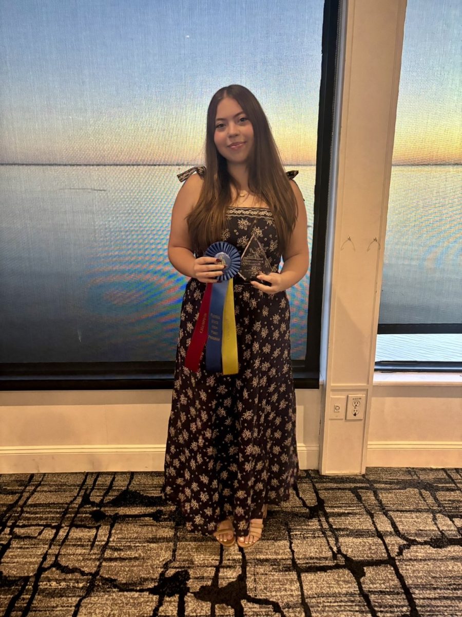 Autumn stands posing with a ribbon with a smile. The Rusty Pelican crowned her the equitation champion for the 2025 meet, remembering her skills and effort.